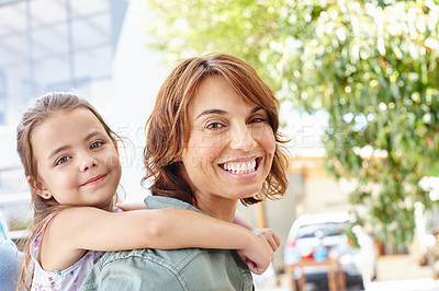 Buy stock photo Shot of a mother giving her daughter a piggyback ride outside