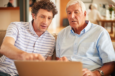 Buy stock photo Shot of a man showing his father something on a laptop