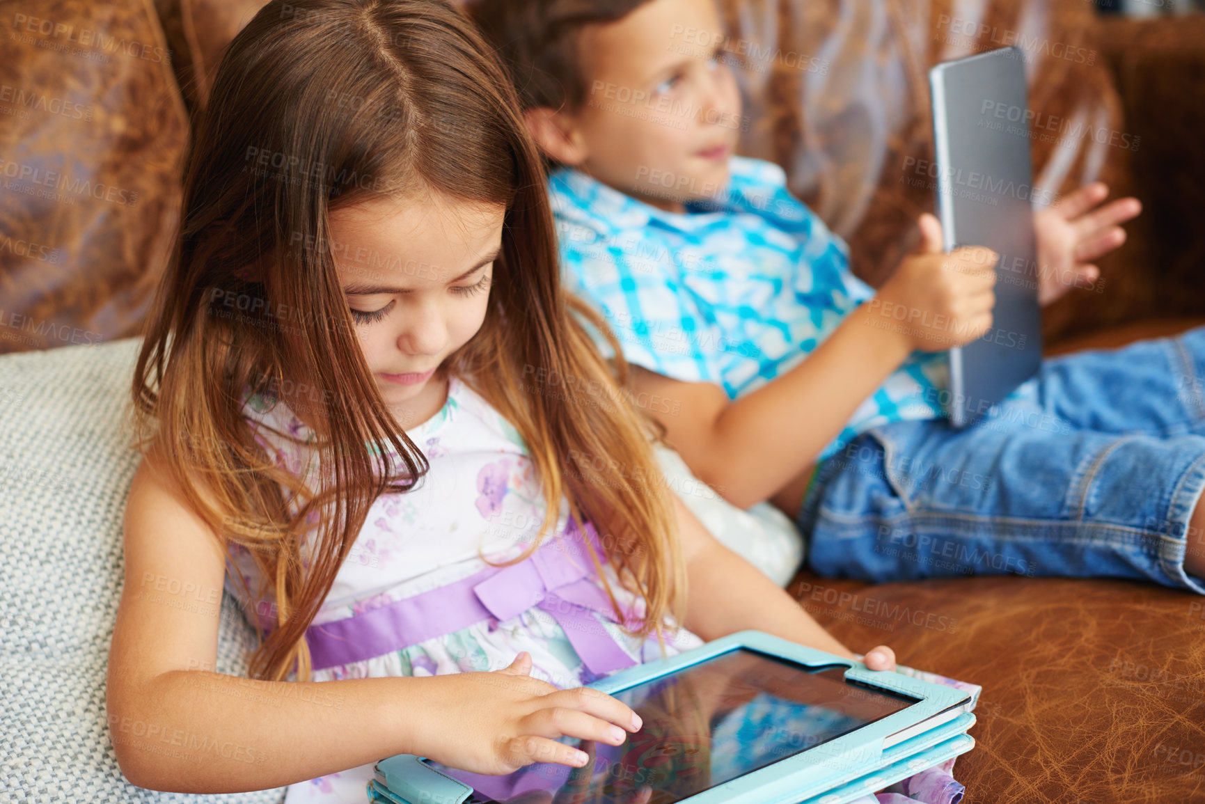 Buy stock photo Shot of a brother and sister using a digital tablet at home