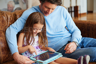 Buy stock photo Shot of a little girl and her dad using a digital tablet at home