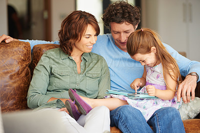 Buy stock photo Shot of a little girl and her parents using a digital tablet at home