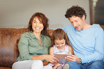 Buy stock photo Shot of a little girl and her parents using a digital tablet at home