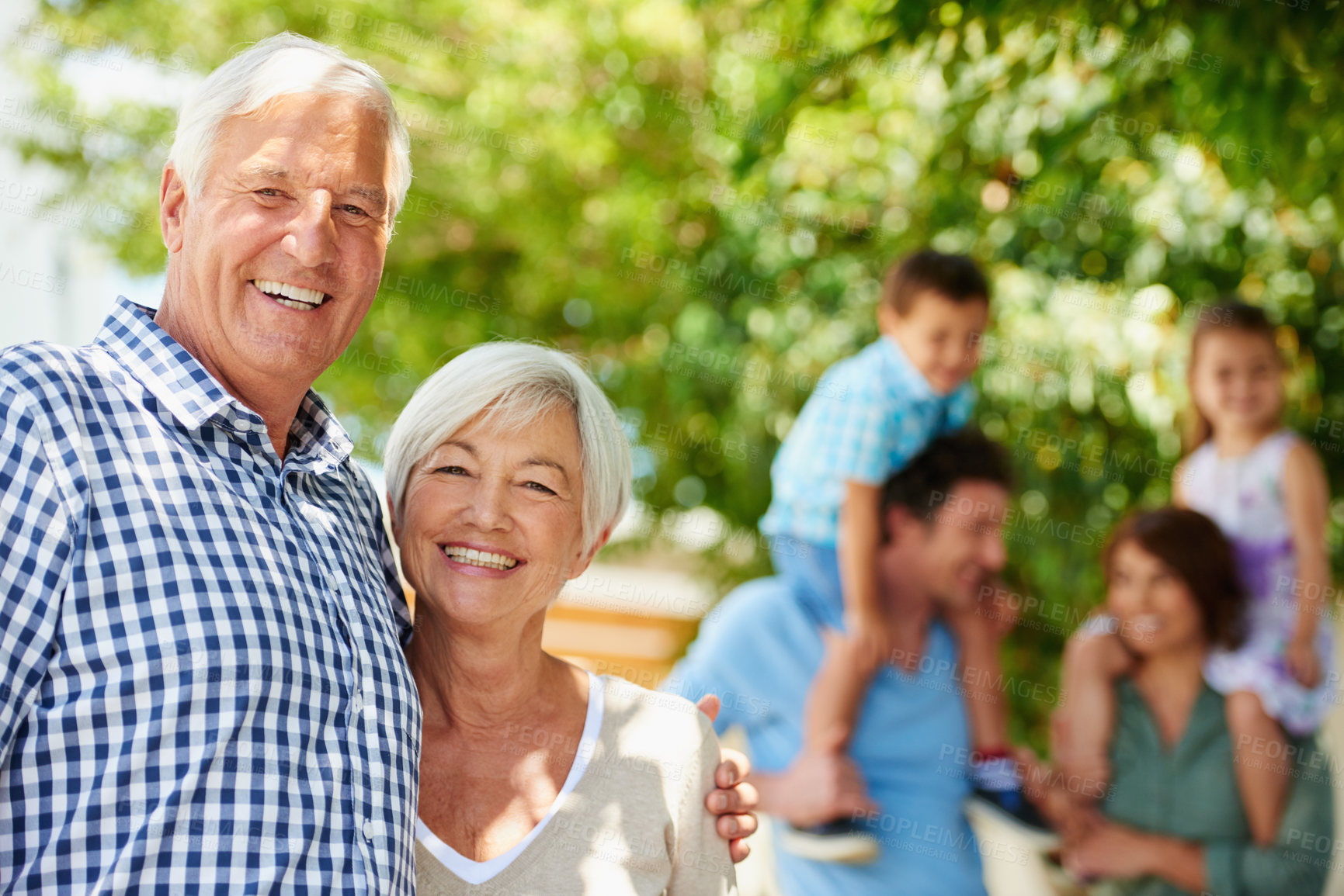Buy stock photo Shot of a happy senior couple with their family standing in the background