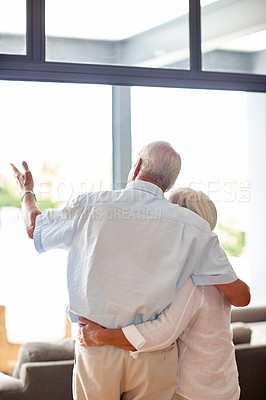 Buy stock photo Rearview shot of a senior couple looking through their living room window