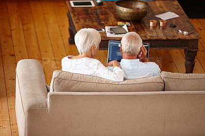 Buy stock photo Rearview shot of a senior couple using a digital tablet at home