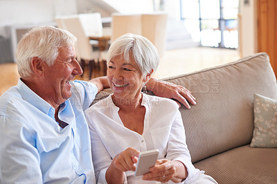 Buy stock photo Shot of a senior couple using a cellphone together