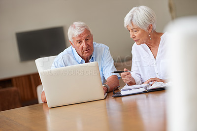Buy stock photo Shot of a senior couple going over some paperwork while using a laptop