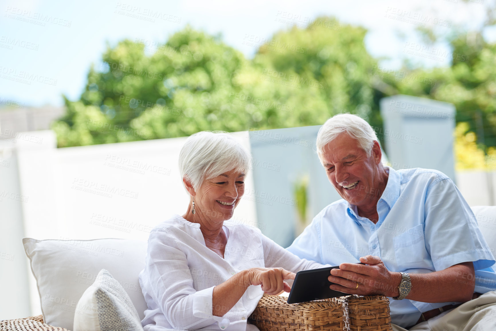 Buy stock photo Shot of a senior couple using a tablet while sitting on their patio9