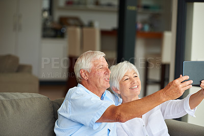 Buy stock photo Shot of a senior couple taking a selfie with their tablet