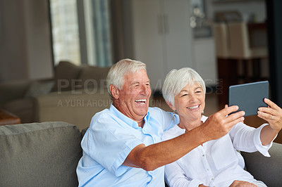 Buy stock photo Shot of a senior couple taking a selfie with their tablet at home