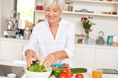 Buy stock photo Shot of a senior woman making a salad in her kitchen