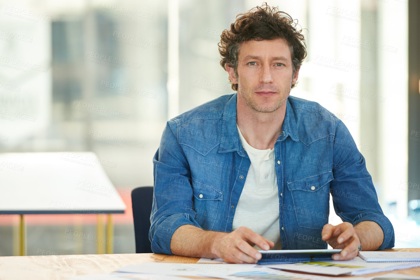 Buy stock photo A young man working on a digital tablet in the office