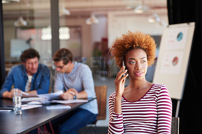 Buy stock photo A young woman talking on her cellphone during a meeting in an office