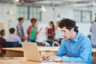 Buy stock photo Cropped shot of a handsome businessman working in the office with his colleagues in the background