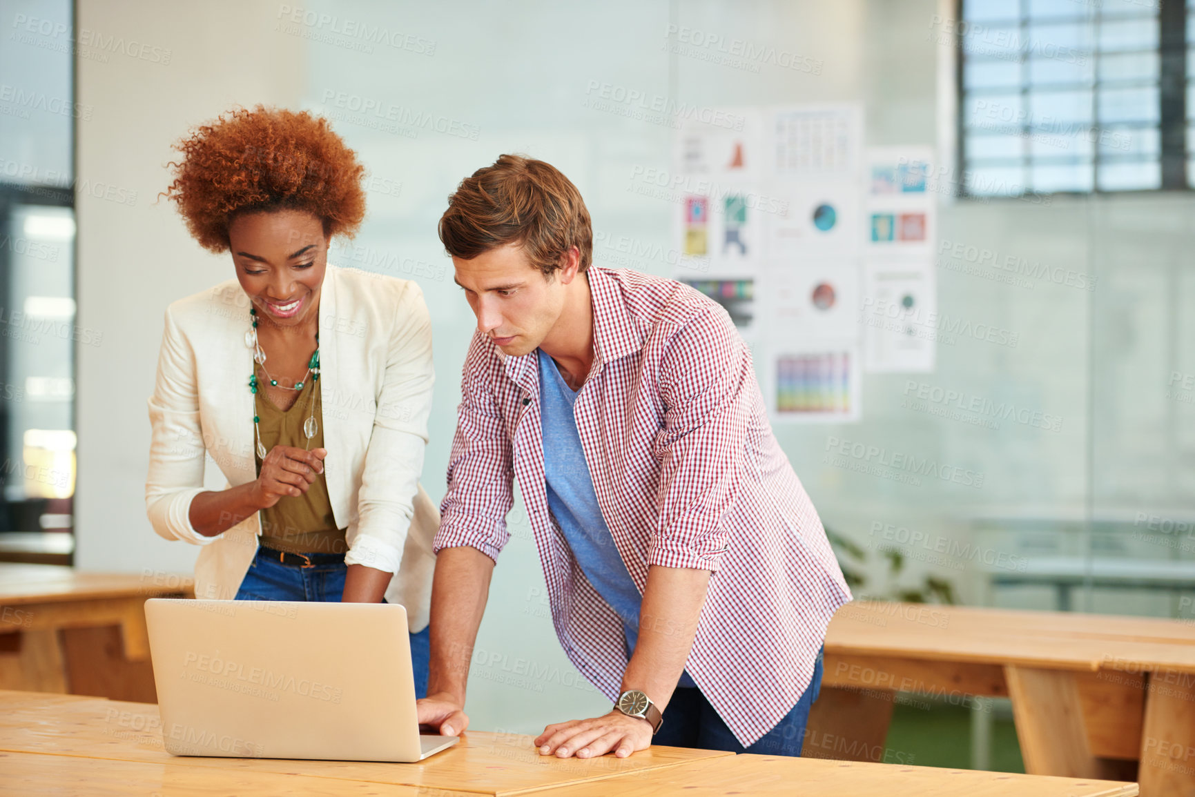 Buy stock photo Shot of two young coworkers working together on a laptop together