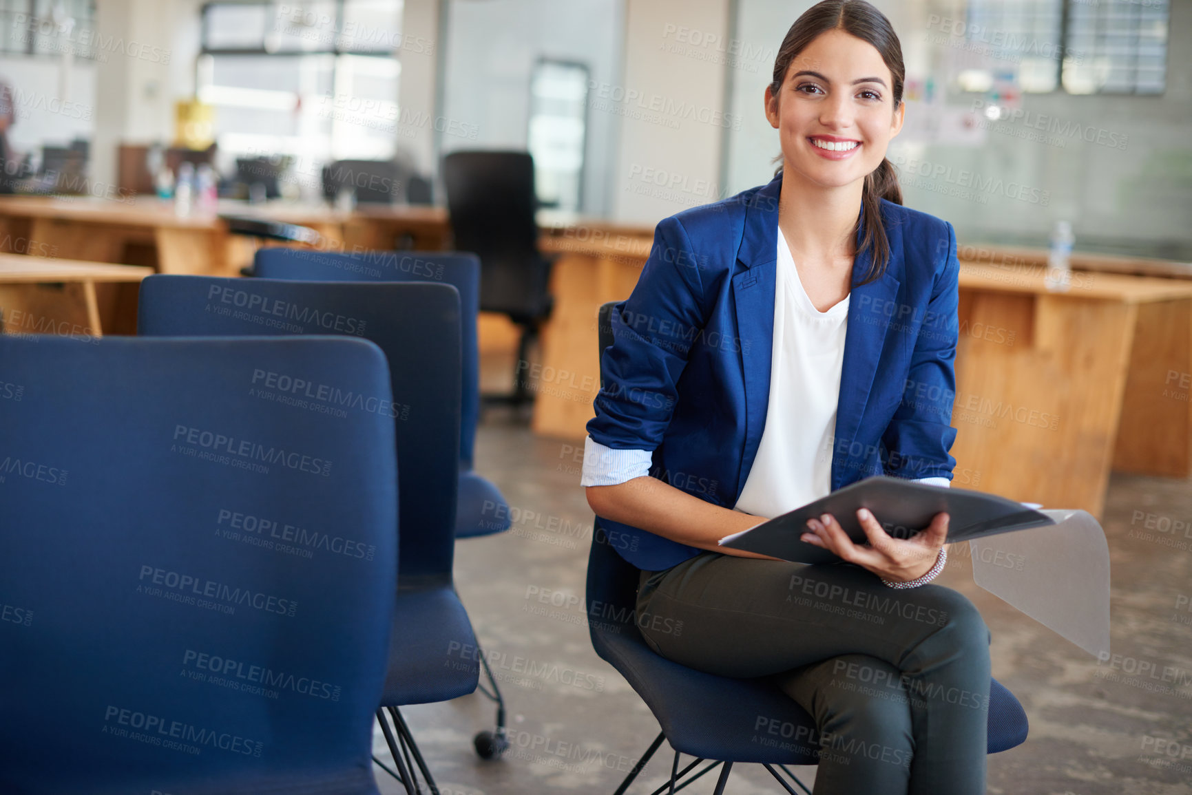 Buy stock photo Shot of a young businesswoman sitting in an office holding paperwork