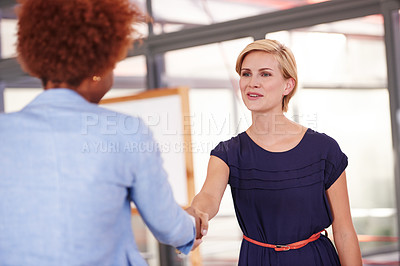 Buy stock photo Cropped shot of two businesswomen shaking hands in an office