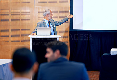 Buy stock photo Senior, businessman and leader with presentation on projector for meeting, seminar or conference at office. Man spokesperson, CEO or speaker talking on podium to group, corporate audience or workshop