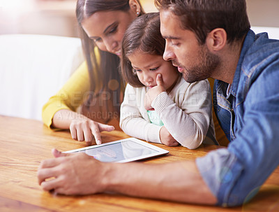 Buy stock photo Shot of young parents showing their little daughter how to use a tablet