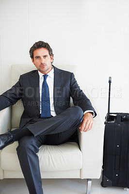 Buy stock photo Business man sitting on a chair with a wheeled upright besides him