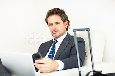 Buy stock photo Business man using cellphone and laptop and sitting on a chair with luggage
