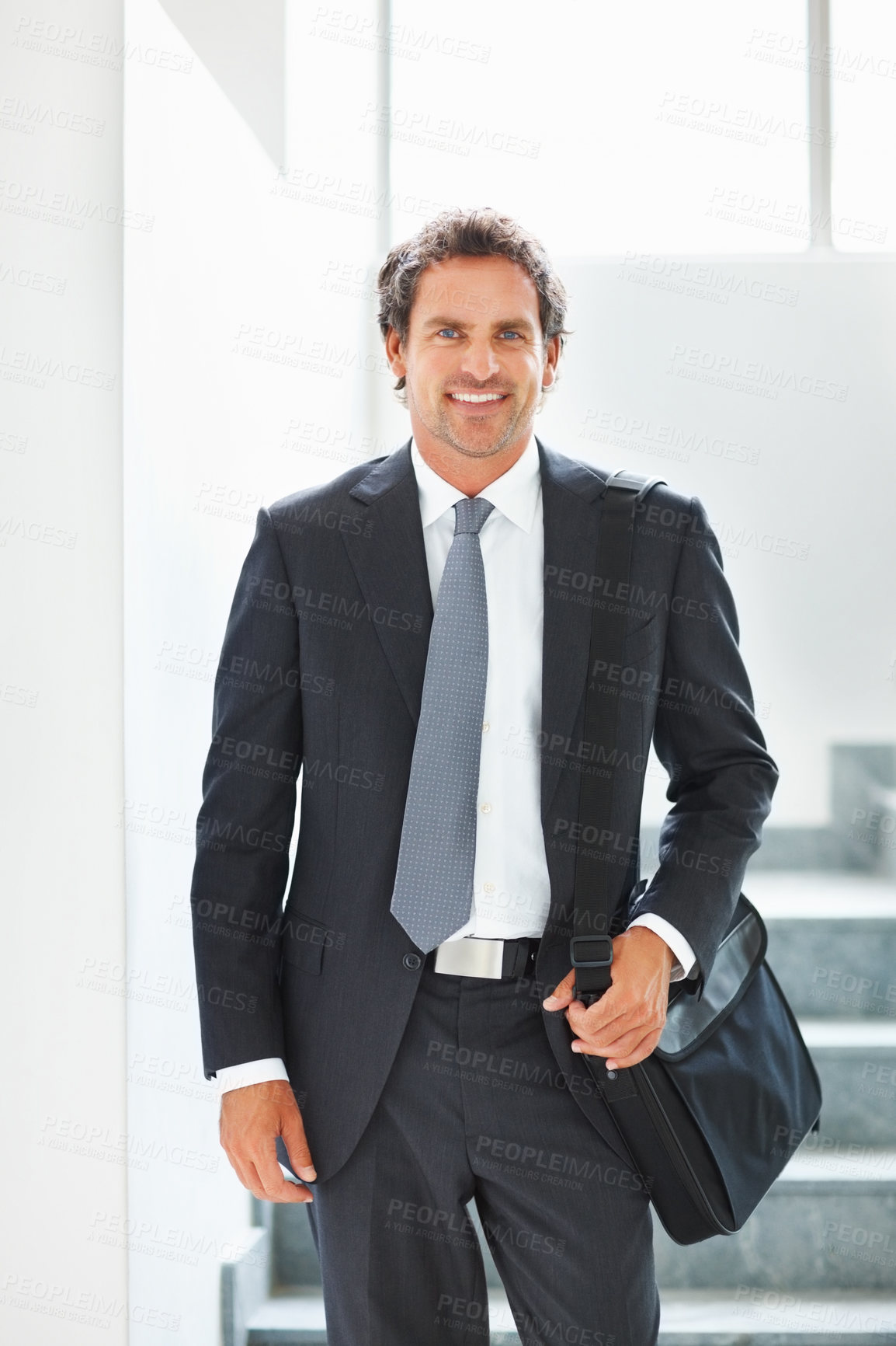 Buy stock photo Happy, businessman and walking down stairs in portrait with laptop bag in office for travel. Smile, male person or entrepreneur with luggage for corporate trip or commute to conference or convention