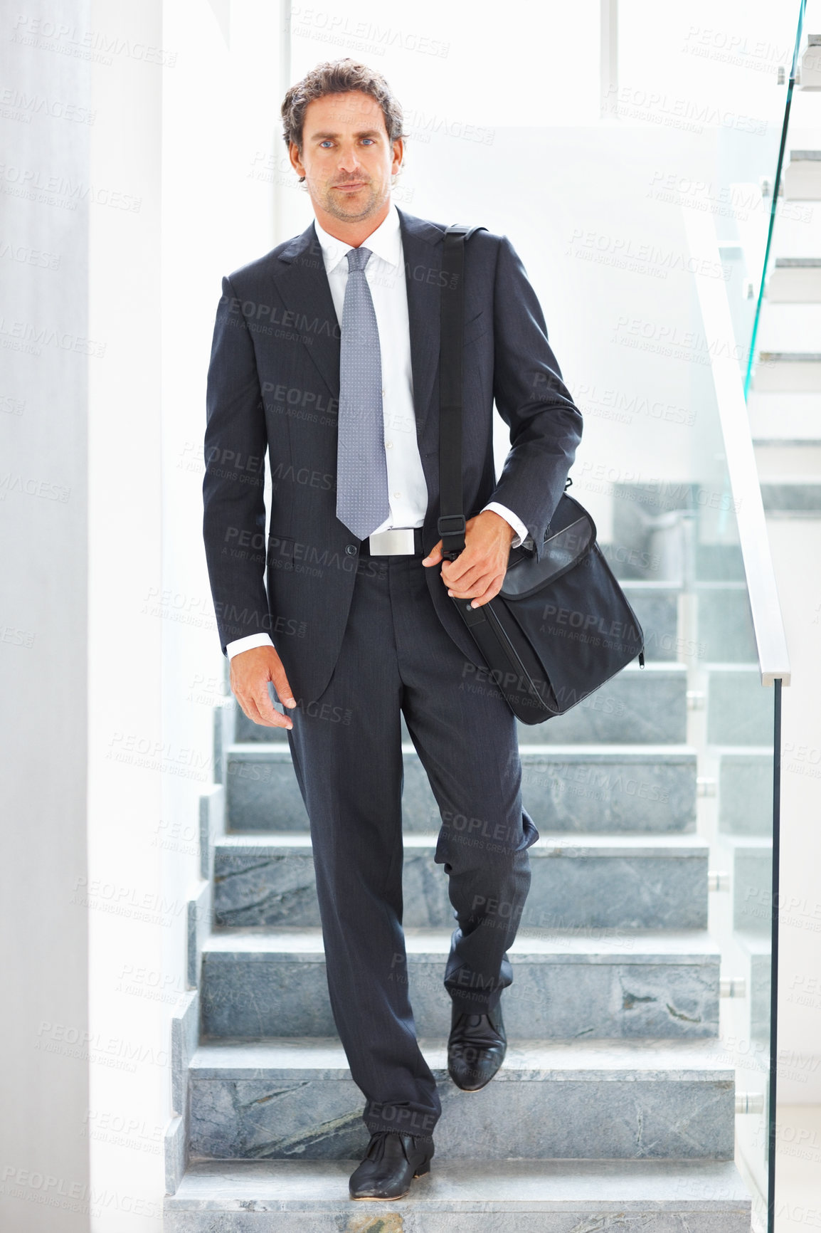 Buy stock photo Happy, businessman and walking down stairs with bag in office lobby for travel. Smile, male person or entrepreneur with luggage for corporate trip or commute to conference or leadership seminar