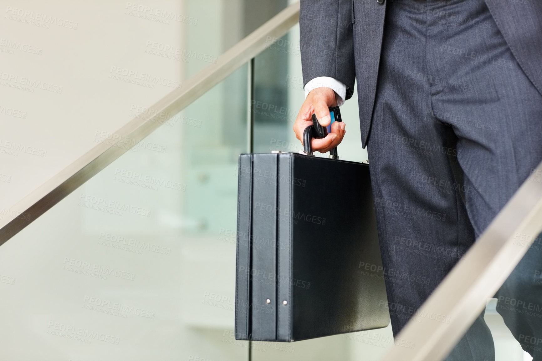 Buy stock photo Low section of business man carrying a cellphone and suitcase and walking down the stairs