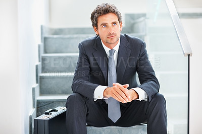 Buy stock photo Thoughtful business man sitting on the stairs with a suitcase