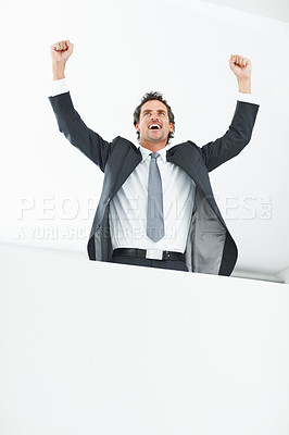 Buy stock photo Low angle view of smart middle aged executive celebrating with hands raised near wall