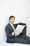 Business man smiling and reading newspaper