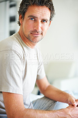 Buy stock photo Portrait, relax and a mature man in the bedroom of his home to relax on a morning of the weekend. Face, wellness and happy with a confident person in casual pajamas sitting on a bed in his apartment