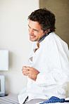 Man buttoning shirt and talking on mobile phone