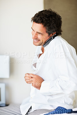 Buy stock photo Phone call, home and business man dressing in bedroom getting ready for work, job and career. Technology, communication and happy person button shirt on cellphone for conversation, chat and contact
