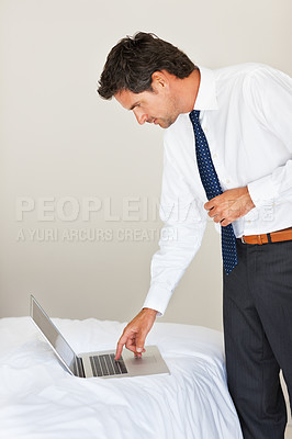 Buy stock photo Laptop, bedroom and a business man getting ready for work at his home in the morning while checking an email. Corporate, computer on a bed and a professional employee dressing in his apartment