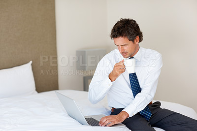 Buy stock photo Laptop, bedroom and tea with a businessman getting ready for work at his home in the morning while checking an email. Corporate, computer on a bed and an employee drinking coffee in an apartment