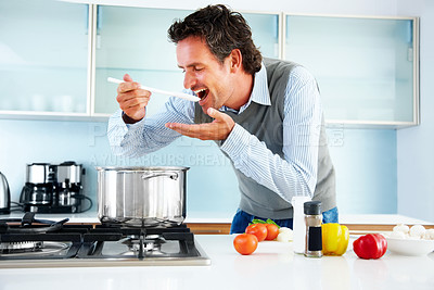 Buy stock photo Portrait of a mature man tasting the food he is cooking
