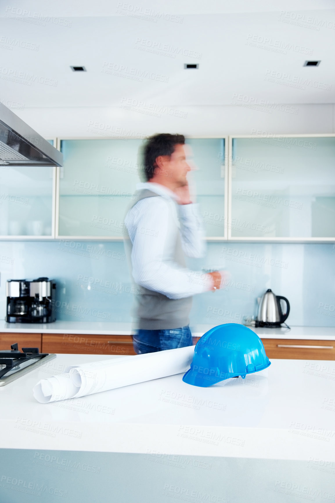 Buy stock photo Architect, phone call and busy man in conversation for planning building project, development and talkinh in kitchen. Engineer, blur and remote work for construction with helmet and blueprint in home