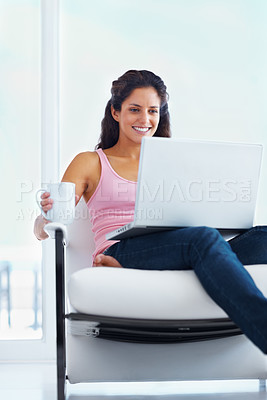 Buy stock photo Woman, happy and coffee with laptop with reading digital blog and relax wellness in chair in home. Young person, smile and computer with espresso for online subscription and technology in apartment