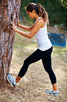 Young woman stretching against a tree