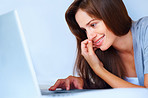 Smiling female working on laptop while on the bed