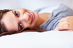 Smiling sweet female lying comfortably in bed