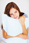 Pretty thoughtful female hugging a pillow in bed