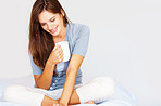 Pretty female sitting thoughtfully in bed with coffee