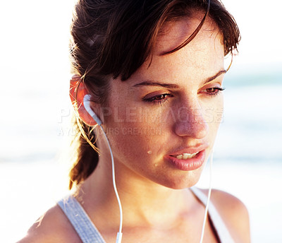 Buy stock photo Tired, runner and woman rest on beach with sweat from exercise or listening to music in headphones. Athlete, thinking and streaming podcast at ocean or running at sea for training with fatigue