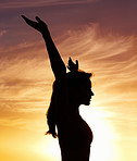 Freedom - Woman with arms raised at sunset