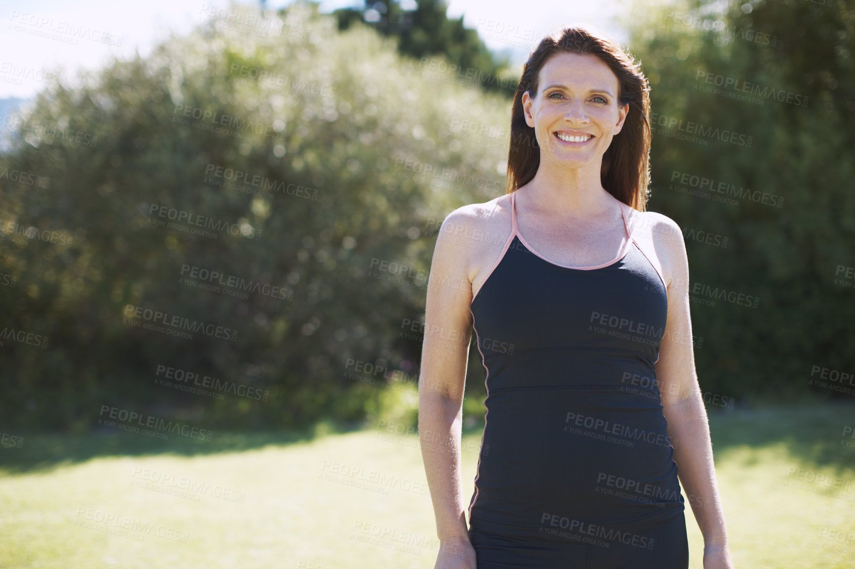 Buy stock photo An attractive woman in sports clothing smiling while standing in the outdoors