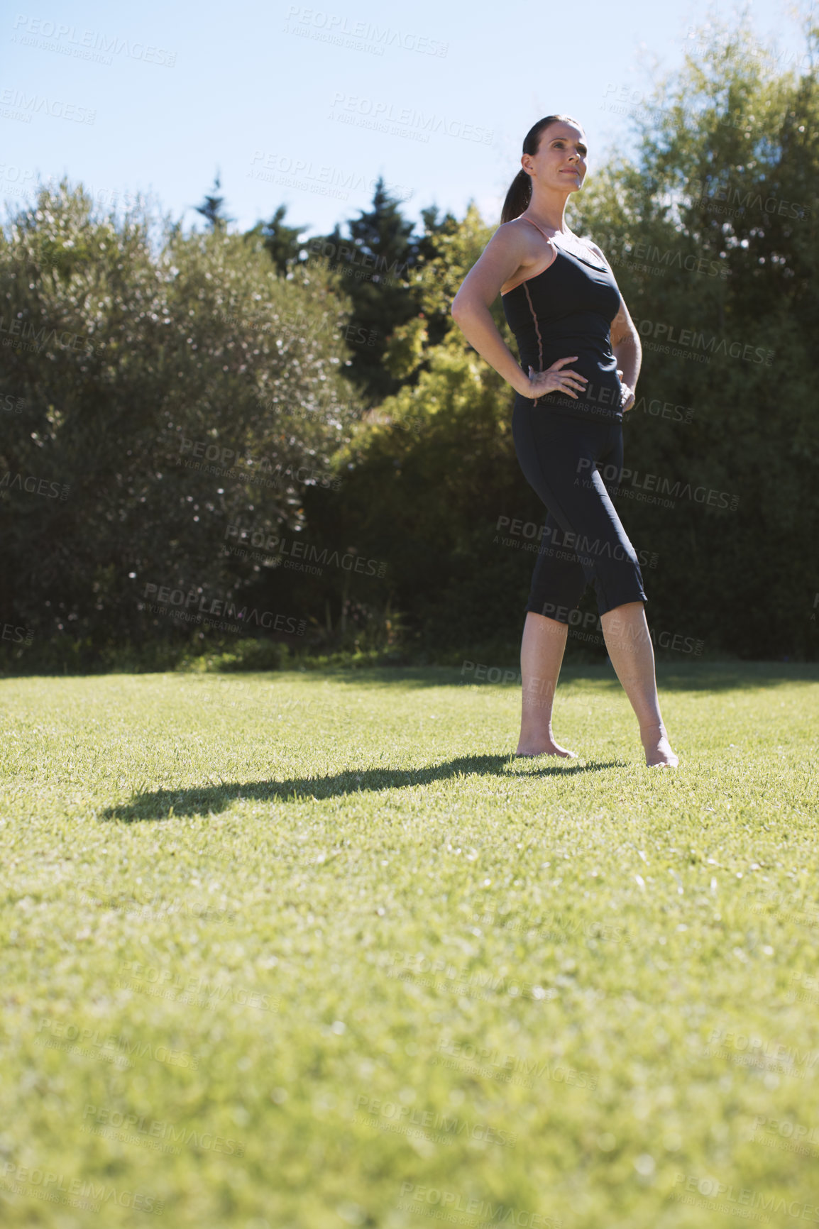 Buy stock photo An attractive brunette standing and stretching with her hands on her hips