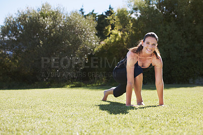 Buy stock photo Portrait of an attractive brunette doing some stretching exercises on the grass