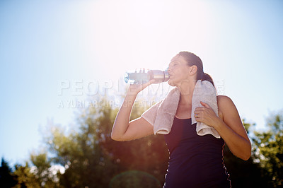 Buy stock photo An attractive woman drinking from her water bottle after a workout